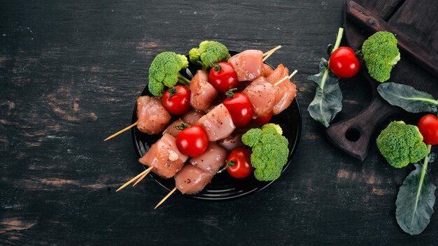 Rohe Hühnerspieße mit Tomaten und Gemüse Kebab auf einem hölzernen Hintergrund Draufsicht Kopierbereich