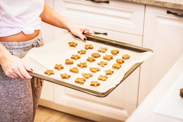 Rohe Ingwerplätzchen auf Backblech in den Frauenhänden