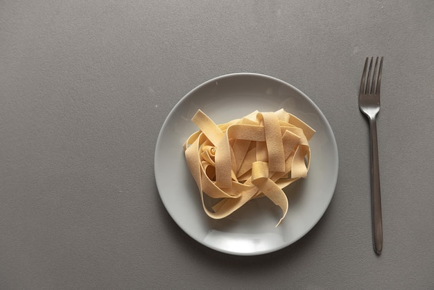 Rohe italienische Pasta auf einem grauen Teller auf grauem Hintergrund