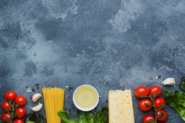 Rohe italienische Pasta Spaghetti und Kochen Zutaten Kirschtomaten Käsegrüns