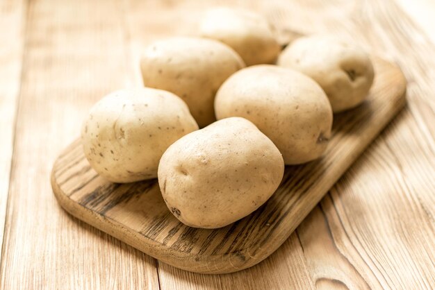 Rohe Kartoffelknollen auf einem hölzernen Hintergrund