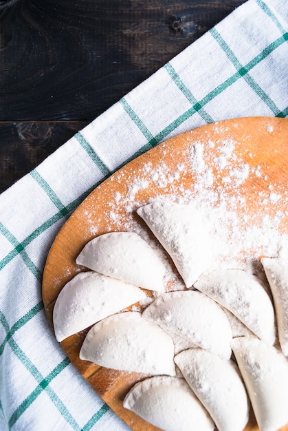 Rohe Knödel bestreut mit Mehl auf einem Küchenbrett und einem gestreiften Tuch