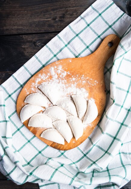 Rohe Knödel bestreut mit Mehl auf einem Küchenbrett und einem gestreiften Tuch