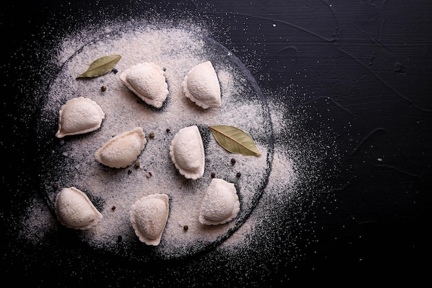 Rohe Knödel mit Kartoffeln auf schwarzem Hintergrund. Vareniki ist ein Gericht der slawischen Küche.