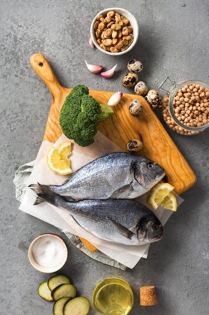 Rohe Kochzutaten für leckeres und gesundes Essen. Frischer Fisch, Gemüse und Hülsenfrüchte auf grauer Hintergrundoberansicht