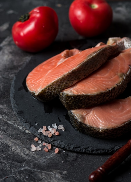 Rohe Lachse, Tomaten und Salz auf Marmortabelle.