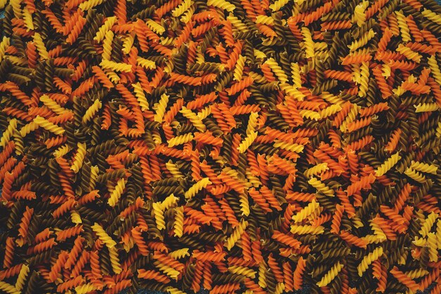 Rohe mehrfarbige Tricolore Fusilli Nudeln auf blauem Betonhintergrund verstreut