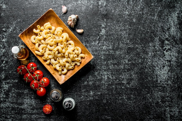 Rohe Nudeln auf einem Teller mit Tomaten, Knoblauch und Gewürzen