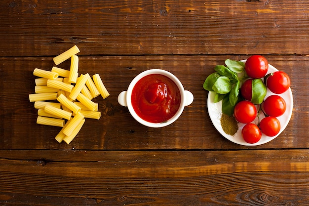 Rohe Pasta-Geschmackssauce in der Schüssel und rote frische Kirschtomaten für die Zubereitung des Frühstücks Draufsicht