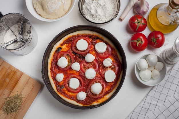 Rohe Pizza Margarita mit Bestandteilen.