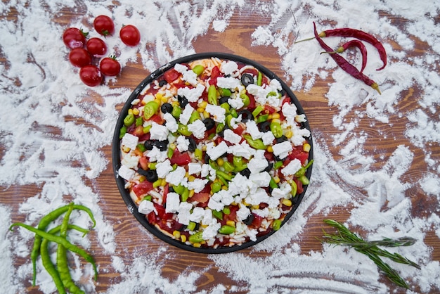 Rohe Pizza mit Mehl und Gemüse