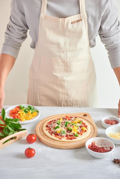 Rohe Pizza mit Zutaten im Hintergrund