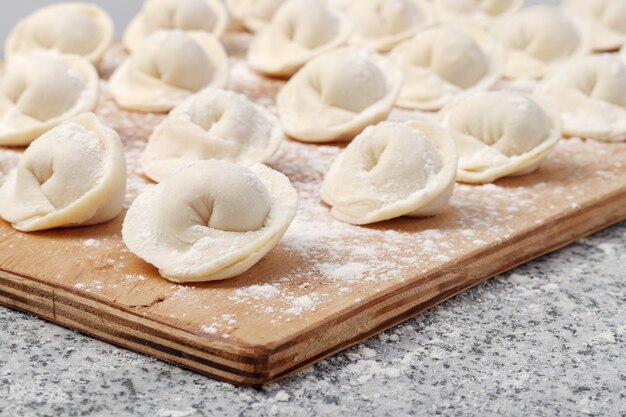 Rohe Ravioli auf Holzbrett auf Steintisch