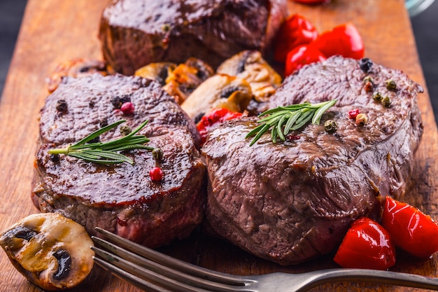 Rohe Rindersteaks auf Holzbrett mit Gewürzen und Kräutern.