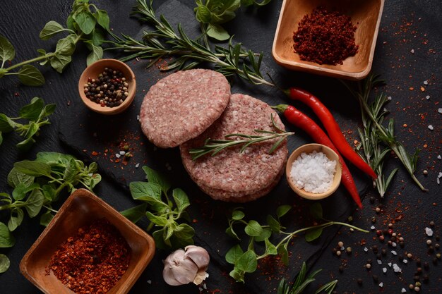 Rohe Rindfleisch-Hamburger-Pastetchen mit Kräutern und Gewürzen. Rohe Burgerkoteletts auf Betonuntergrund