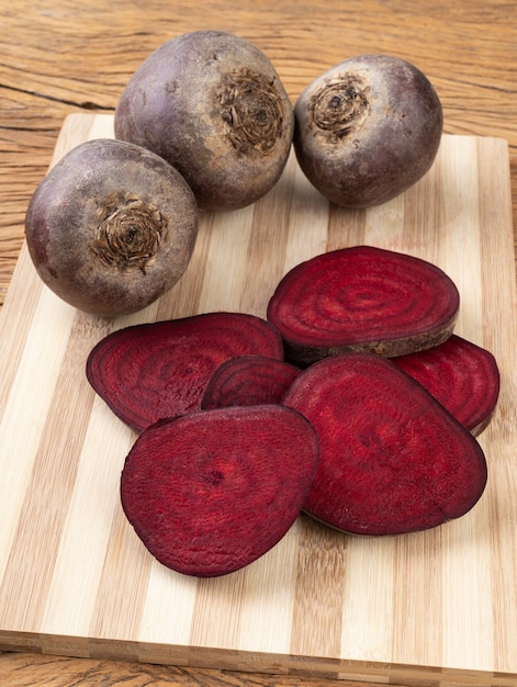 Rohe Rote Beete mit Scheiben auf einem Holztisch.