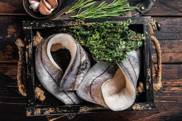 Rohe Schellfischfilets in Holzschale mit Rosmarin und Thymian Draufsicht auf Holzhintergrund