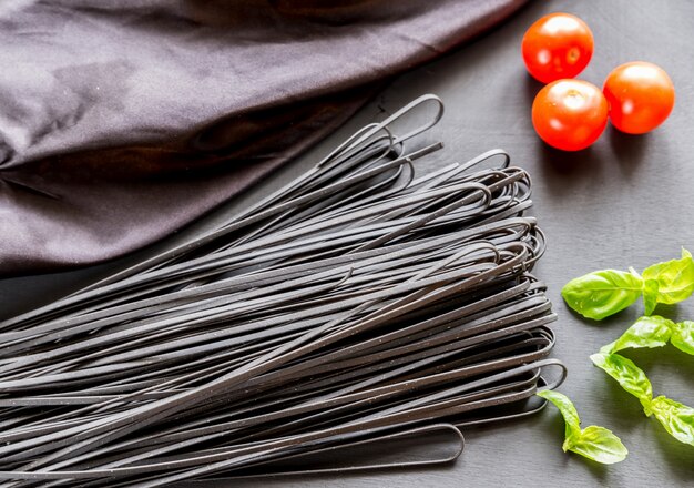 Rohe schwarze Nudeln mit Basilikum und Tomaten