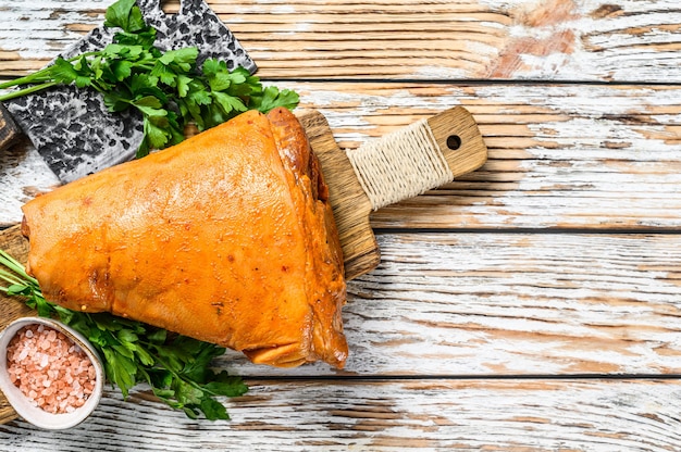 Rohe Schweinekeule mit Kräutern und auf weißem Tisch marinieren. Holztisch. Draufsicht.