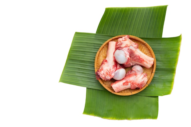 Rohe Schweineknochen im Bambuskorb auf Bananenblättern