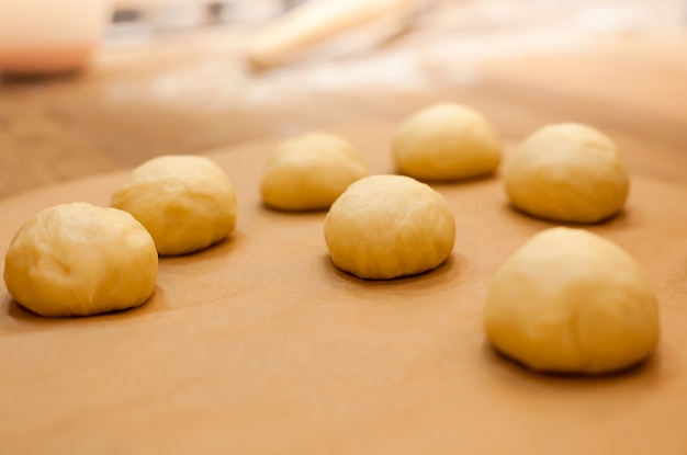 Rohe selbst gemachte Brötchen auf Küchentisch bei der Herstellung