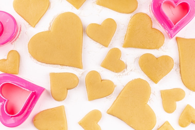 Rohe selbst gemachte herzförmige Plätzchen mit rosa Ausstecher und Mehl