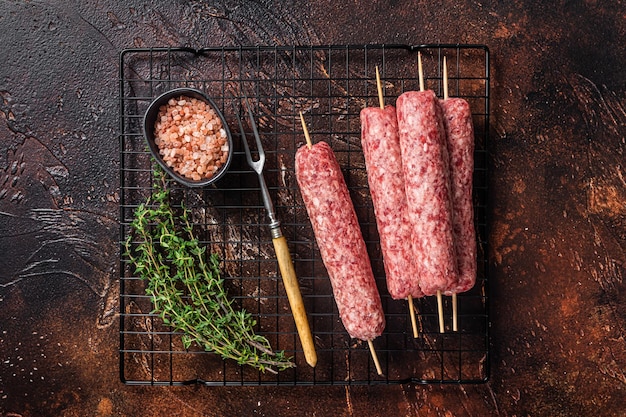 Rohe Souvlaki Shashliks oder Shish Kebab Spieße mit Gewürzen Dunkler Hintergrund Draufsicht