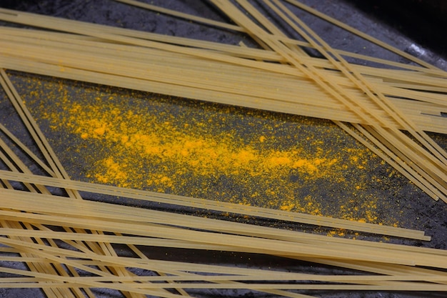 Rohe Spaghetti mit gelben Gewürzen auf dunklem Hintergrund Nahaufnahme einer italienischen Pasta Blick von oben