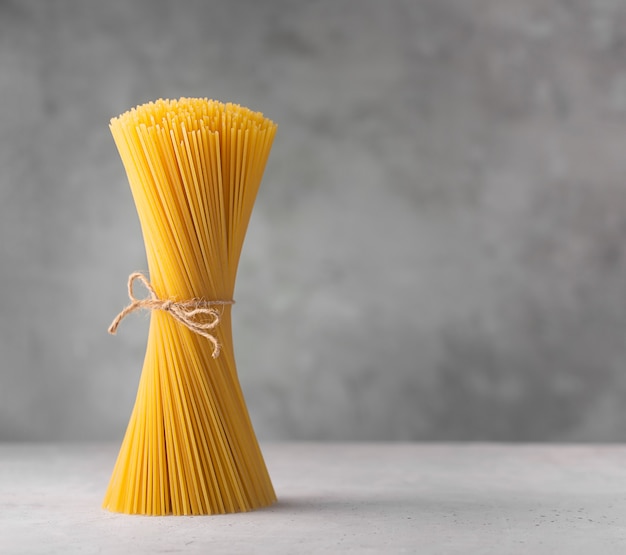 Rohe Spaghetti. Trockene italienische Pasta aus Hartweizen, grauer Hintergrund mit Kopierraum