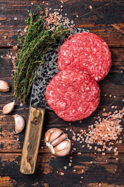 Rohe Steakkoteletts mit Rinderhackfleisch auf einem Metzgererbeil Holzhintergrund Ansicht von oben