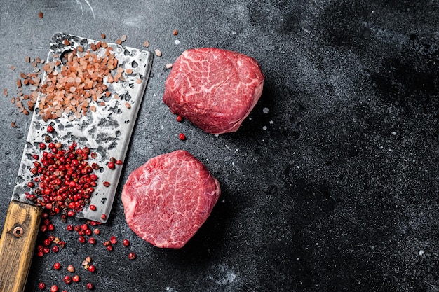 Rohe Steaks Filet Mignon auf einem Fleischerbeil Rinderfilet Schwarzer Hintergrund Draufsicht Platz für Text