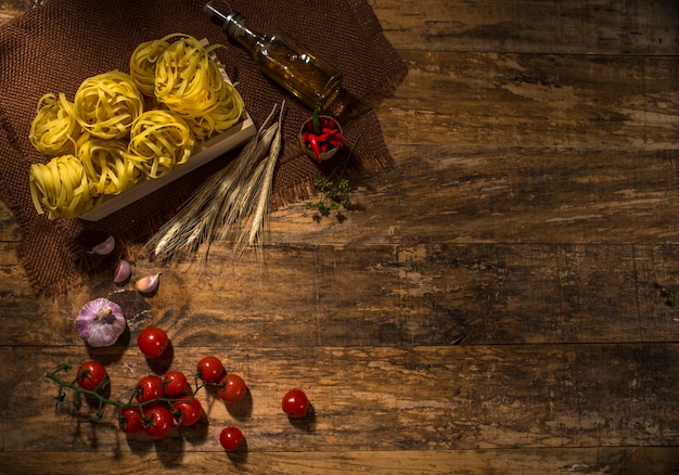 Rohe tagliarini auf holz mit kirschtomaten und knoblauch, draufsicht