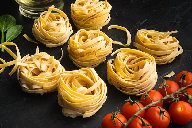 Rohe Tagliatelle-Nester Traditionelles italienisches Pasta-Set auf schwarzem Steinhintergrund