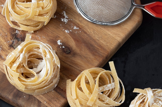 Rohe Tagliatelle-Nudeln auf Schneidebrett.