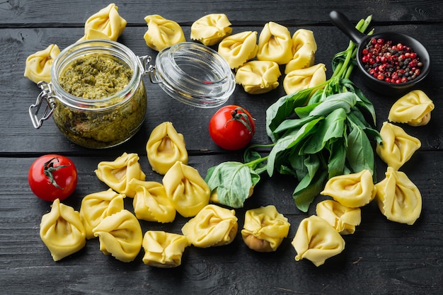 Rohe Tortellini mit Basilikum und Kiefernpesto auf schwarzem Holztisch