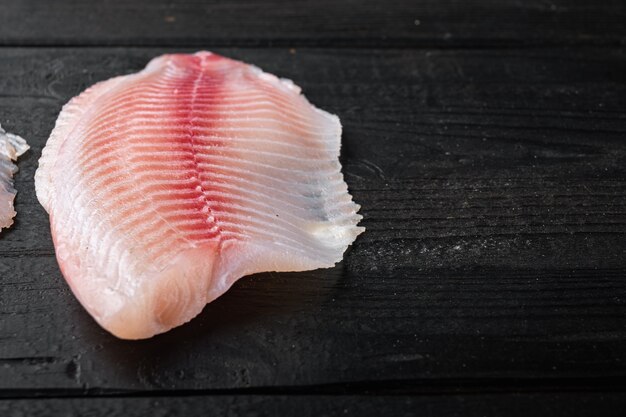 Rohe weiße Fischfiletstücke, auf schwarzem Holztisch