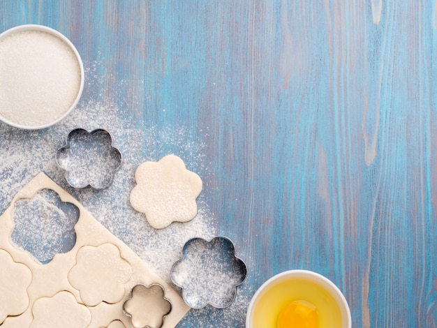 Roher Blätterteig liegt auf einem blauen Holztisch. Zahlen zum Backen von geschnittenen Metallformen