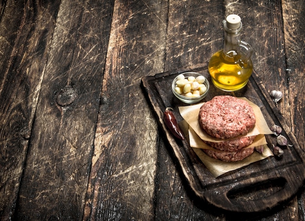 Foto roher burger aus rindfleisch mit gewürzen und olivenöl.