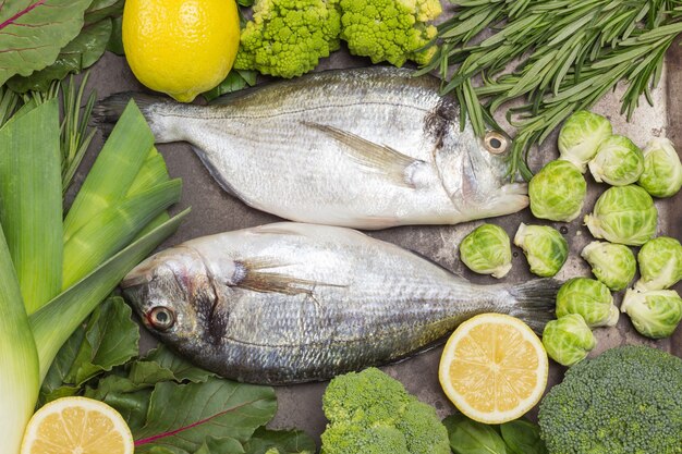 Roher Dorado-Fisch auf Metallschale mit grünem Gemüse und viel Grün