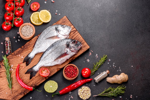 Roher dorado-fisch mit gewürzen, die auf schneidebrett kochen. dorado mit frischem fisch. dorado und zutaten zum kochen auf einem tisch