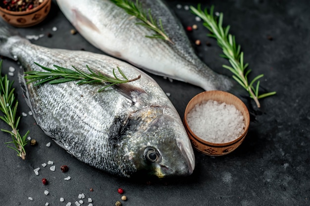 Roher Dorado-Fisch mit Gewürzen und Zutaten Tomate, Rasiermesser, Sonnenblumenöl, Zitrone auf einem Steinhintergrund mit Kopienraum für Ihren Text