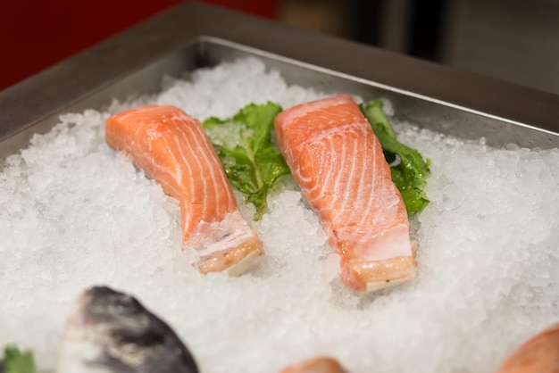 Roher frischer Fisch, der auf dem Bett aus kaltem Eis im Marktstand für Meeresfrüchte gekühlt wird