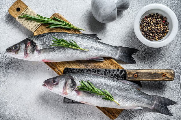 Roher frischer Fisch Seebarsch und Zutaten zum Kochen. Weißer Hintergrund. Draufsicht.