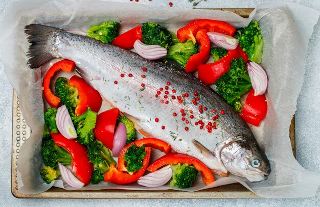 Roher frischer ganzer Fisch (Lachs, Forelle) mit Gemüse