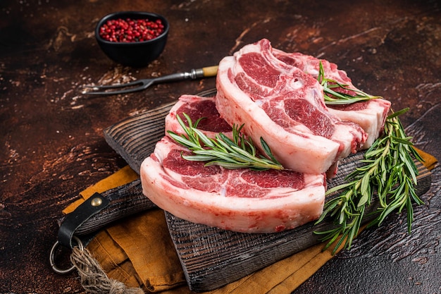 Roher frischer Lammrücken Hammelfleisch mit Kräutern und Gewürzen auf Metzgerbrett Dunkler Hintergrund Ansicht von oben