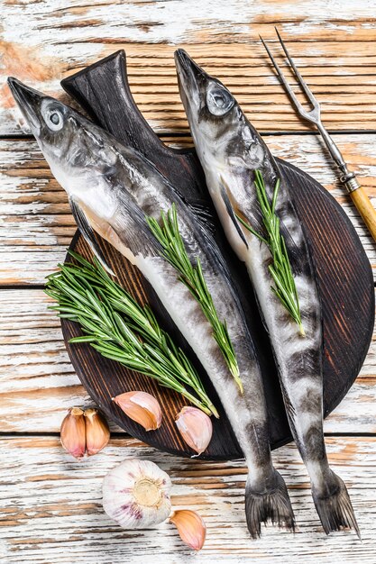 Roher ganzer Eisfisch mit Kräutern. Weißer hölzerner Hintergrund. Draufsicht.