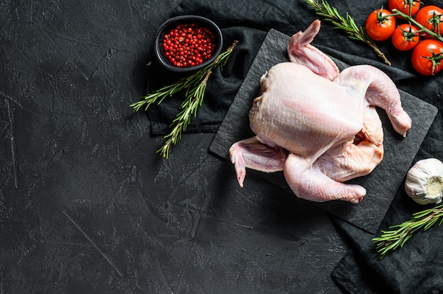 Roher ganzer Poult mit Rosmarin und rosa Pfefferhintergrund