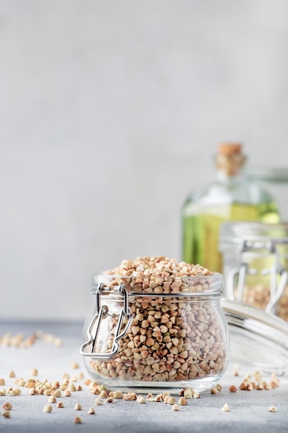 Roher grüner Buchweizen im Glas gesunde vegetarische Kost auf grauem Küchentisch kopieren Raum selektiven Fokus