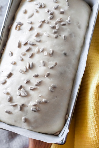 Roher Hefeteig in Zinnform, fertig zum Backen von Brot mit Sonnenblumenkernen