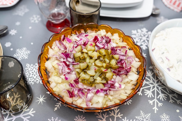 Foto roher hering in öl mit zwiebeln und gurken steht in einer schüssel auf dem weihnachtstisch in polen